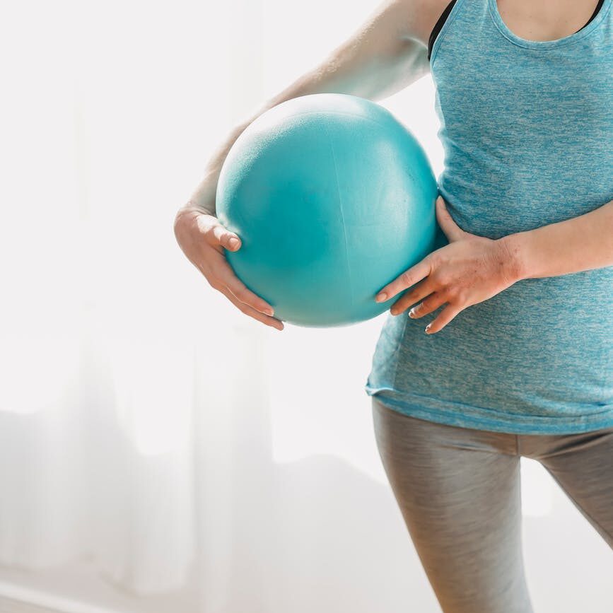 woman with fit ball in light gym